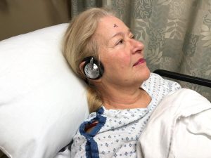 Patient listening to soothing music through headphones while awaiting surgery